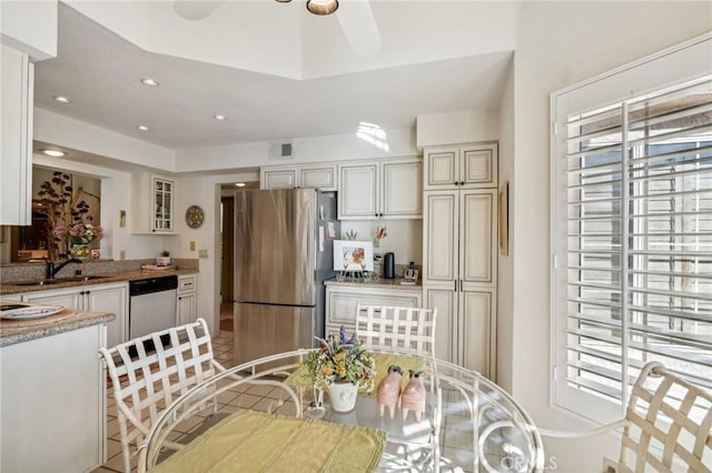 kitchen with white dishwasher, sink, ceiling fan, light stone countertops, and stainless steel refrigerator