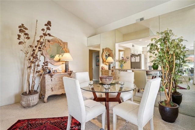 dining area featuring carpet floors and vaulted ceiling