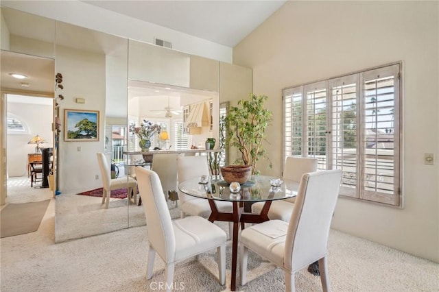 dining room with light carpet, high vaulted ceiling, and ceiling fan