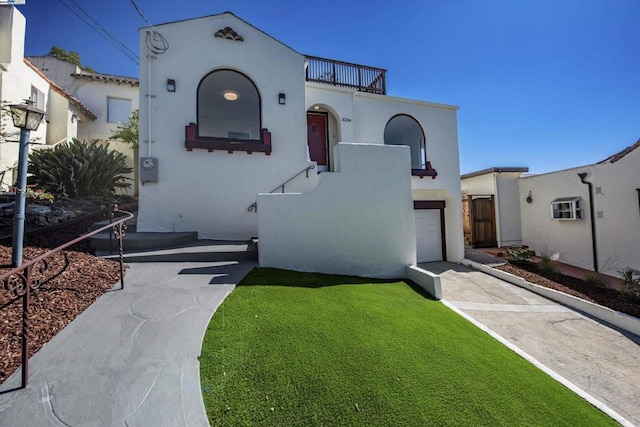 mediterranean / spanish house featuring a front lawn, a garage, and a balcony