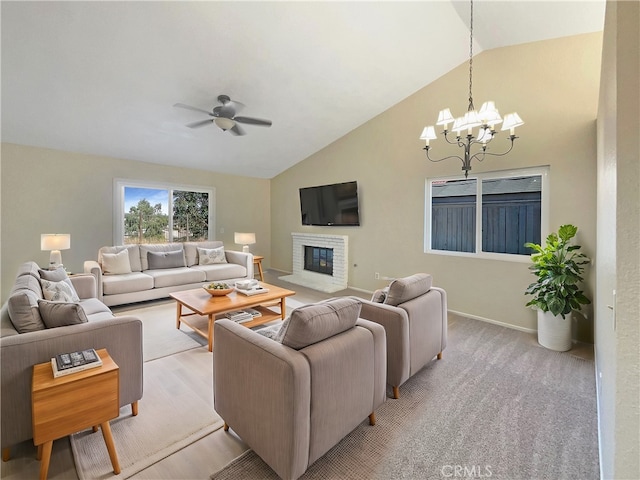 carpeted living room with vaulted ceiling, a brick fireplace, and ceiling fan with notable chandelier