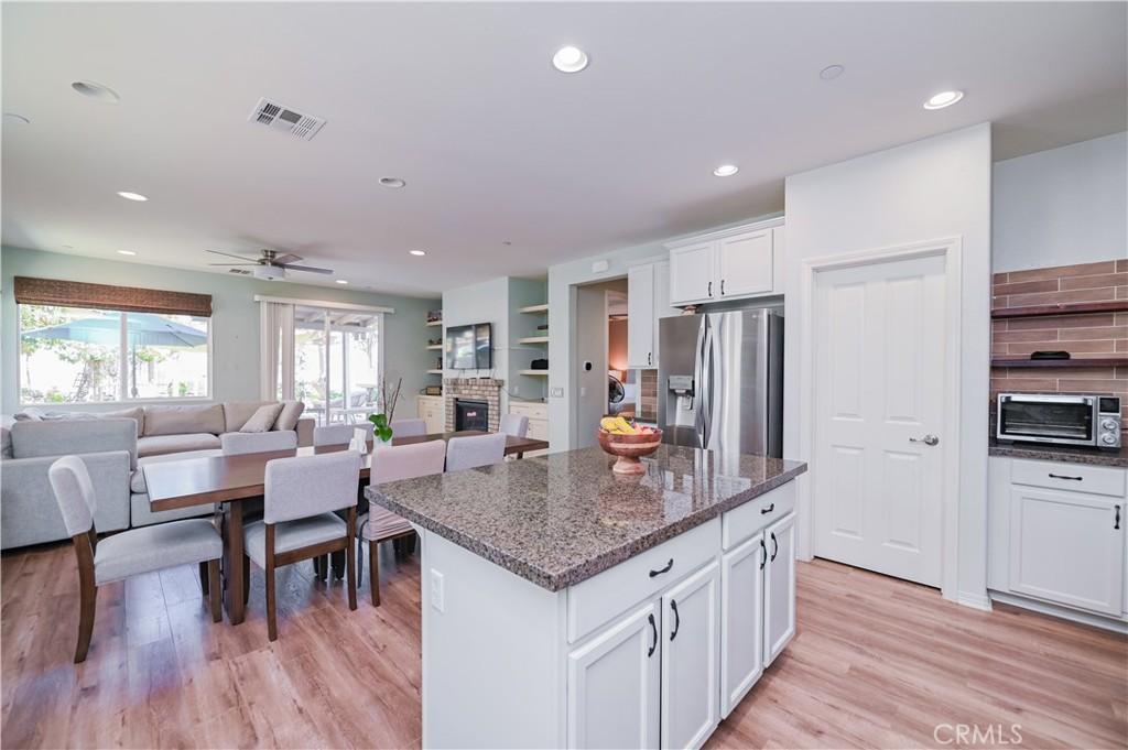 kitchen with white cabinets, stainless steel refrigerator with ice dispenser, dark stone counters, light hardwood / wood-style floors, and a kitchen island