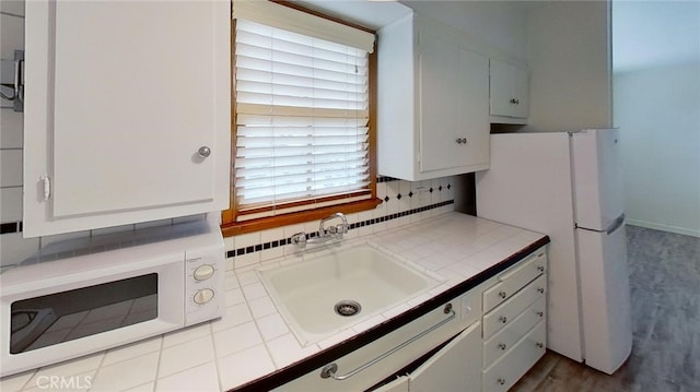 kitchen featuring decorative backsplash, tile countertops, sink, white cabinetry, and white appliances