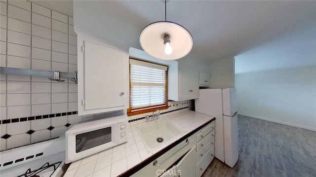 kitchen with sink, decorative backsplash, white cabinetry, and tile counters