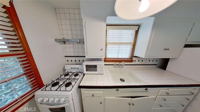 kitchen featuring white cabinets, tasteful backsplash, tile counters, sink, and white appliances