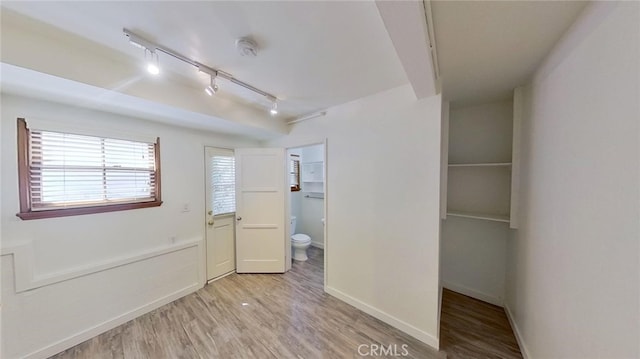 interior space featuring connected bathroom, rail lighting, and light wood-type flooring