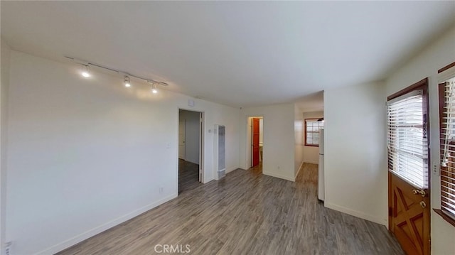 spare room featuring track lighting and light hardwood / wood-style floors