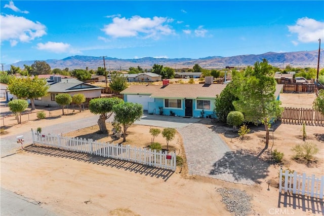 view of front of property with a fenced front yard, curved driveway, and a mountain view