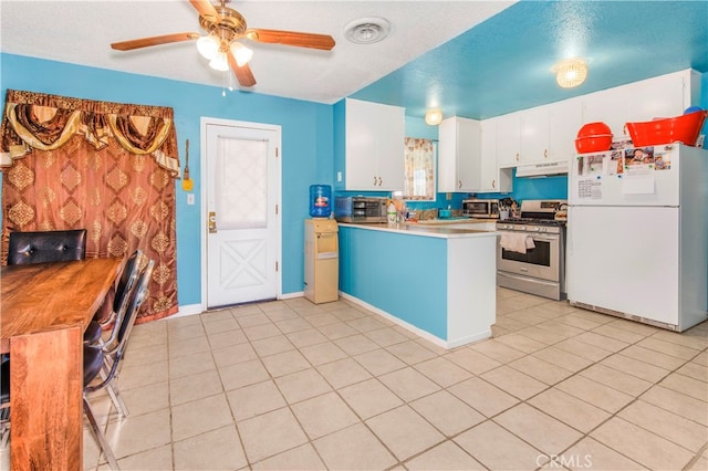 kitchen featuring white refrigerator, light tile patterned floors, stainless steel gas range oven, white cabinets, and ceiling fan