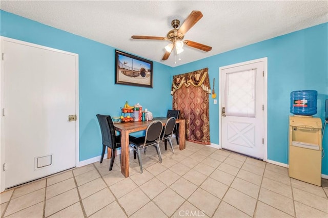 dining space with light tile patterned floors, a ceiling fan, baseboards, and a textured ceiling