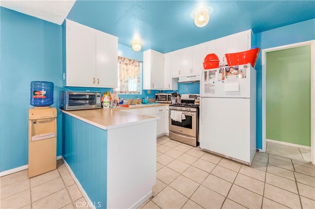 kitchen featuring light tile patterned flooring, sink, stainless steel range with gas cooktop, white cabinets, and white refrigerator