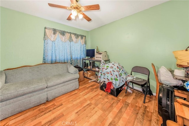 living room featuring baseboards, ceiling fan, and wood finished floors