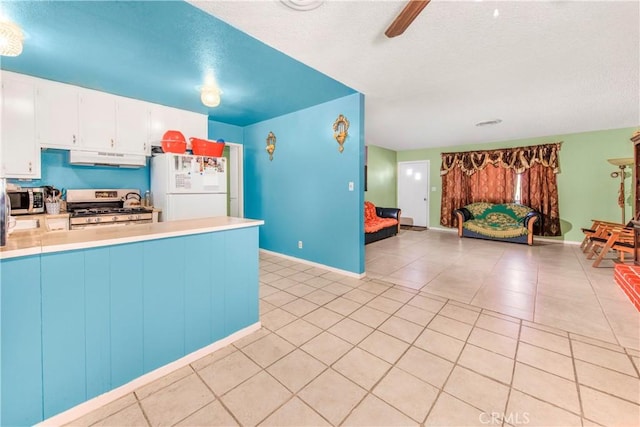 kitchen with under cabinet range hood, open floor plan, stainless steel appliances, light countertops, and light tile patterned floors