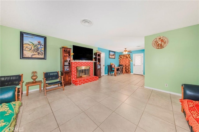 living area with light tile patterned floors, a fireplace, baseboards, and ceiling fan