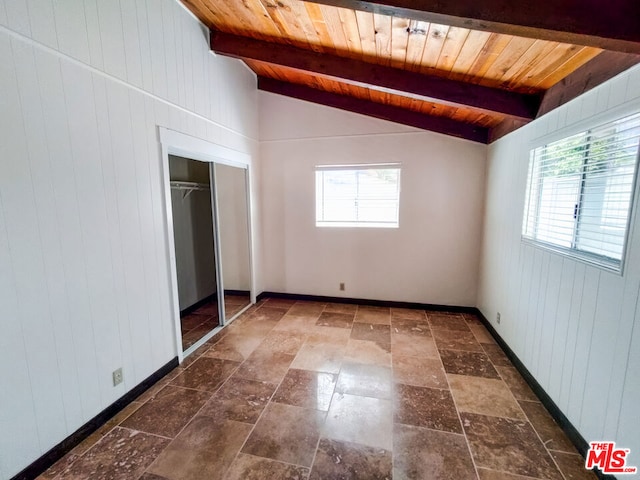 unfurnished bedroom with vaulted ceiling with beams, wooden walls, multiple windows, and wooden ceiling