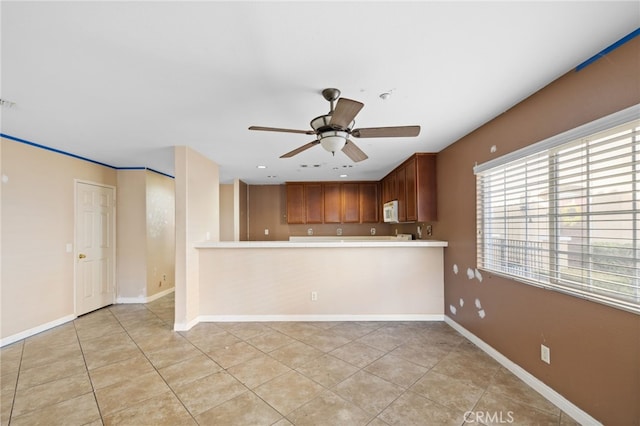 kitchen featuring light tile patterned floors, kitchen peninsula, and ceiling fan