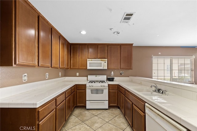 kitchen featuring sink, white appliances, tile countertops, and light tile patterned flooring