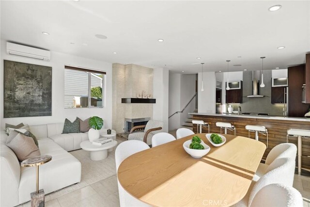 tiled dining room with a wall mounted air conditioner and a fireplace