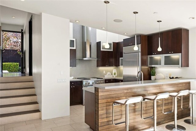 kitchen with high end appliances, tasteful backsplash, dark brown cabinetry, and hanging light fixtures