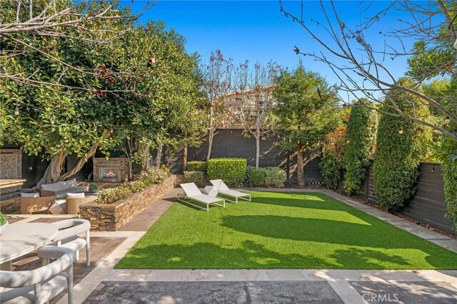 view of yard with an outdoor living space with a fireplace