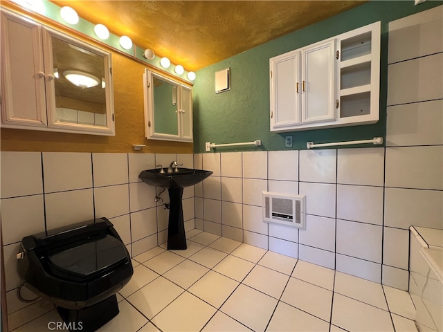 bathroom with heating unit, a textured ceiling, tile walls, sink, and tile patterned flooring