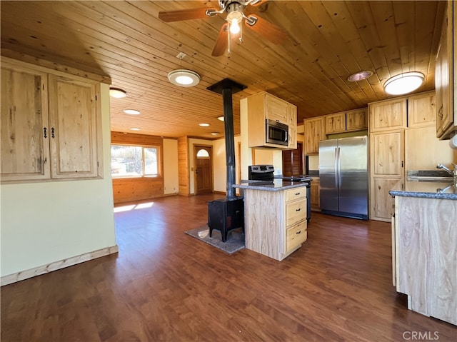 kitchen with light brown cabinets, dark hardwood / wood-style floors, stainless steel appliances, a wood stove, and a center island