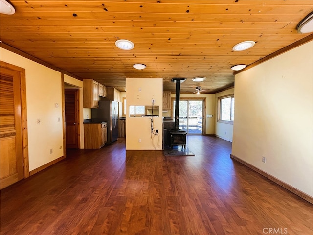 kitchen with stainless steel fridge, dark wood-type flooring, a wood stove, and wooden ceiling