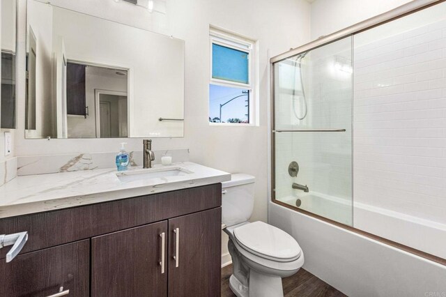 full bathroom with toilet, enclosed tub / shower combo, vanity, and wood-type flooring