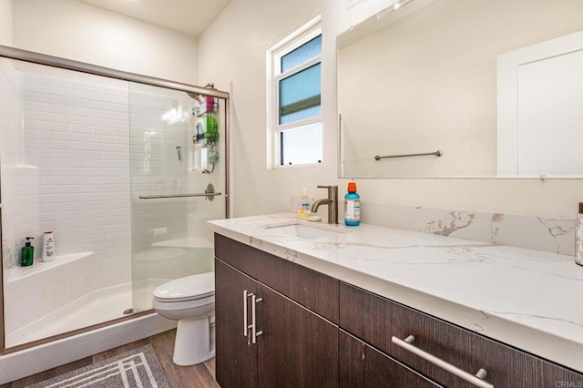 bathroom featuring toilet, hardwood / wood-style flooring, vanity, and a shower with door