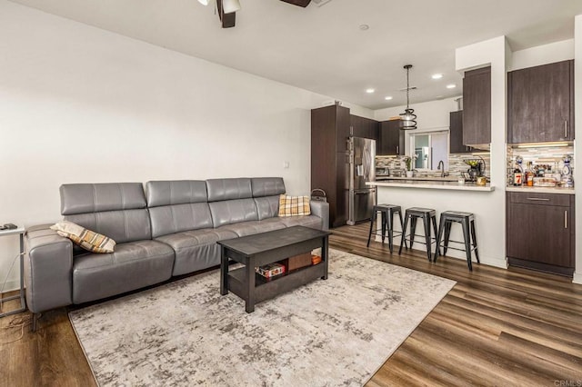 living room featuring sink, dark wood-type flooring, and ceiling fan