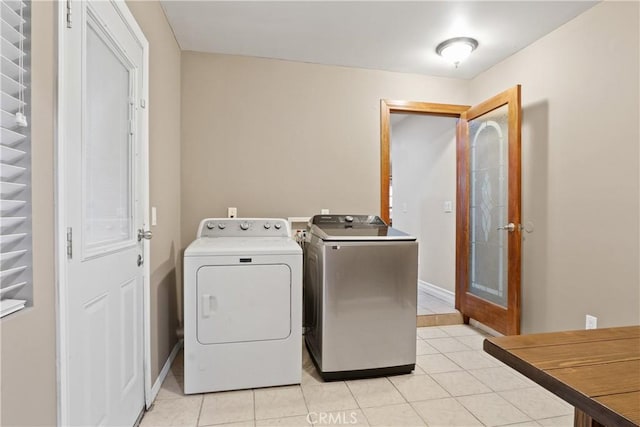 clothes washing area with light tile patterned flooring and independent washer and dryer