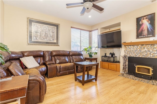 living room with a tiled fireplace, light hardwood / wood-style floors, and ceiling fan