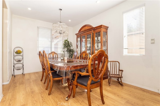 dining space with a notable chandelier, light wood-type flooring, and a wealth of natural light