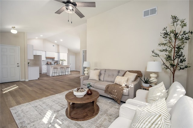 living room with lofted ceiling, hardwood / wood-style flooring, and ceiling fan