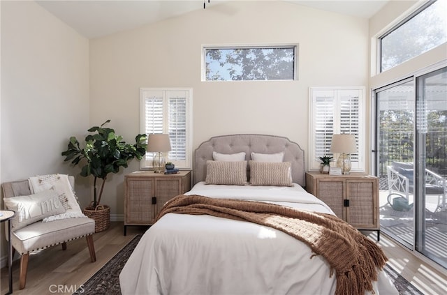 bedroom featuring access to outside, multiple windows, wood-type flooring, and vaulted ceiling