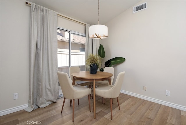 dining room featuring vaulted ceiling and light hardwood / wood-style flooring