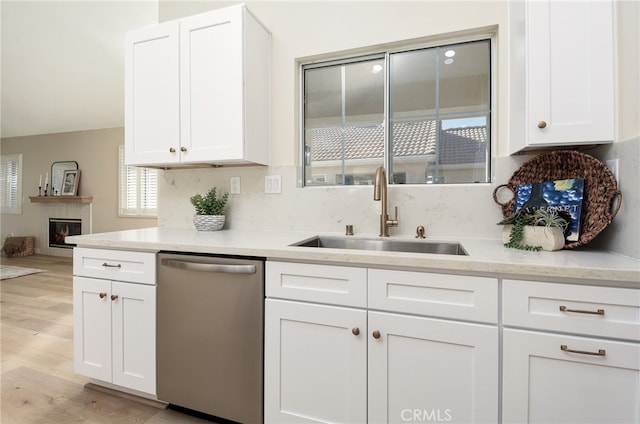 kitchen featuring sink, dishwasher, backsplash, white cabinets, and light hardwood / wood-style flooring