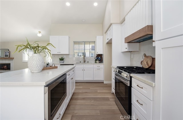 kitchen with appliances with stainless steel finishes, light hardwood / wood-style flooring, white cabinets, and sink