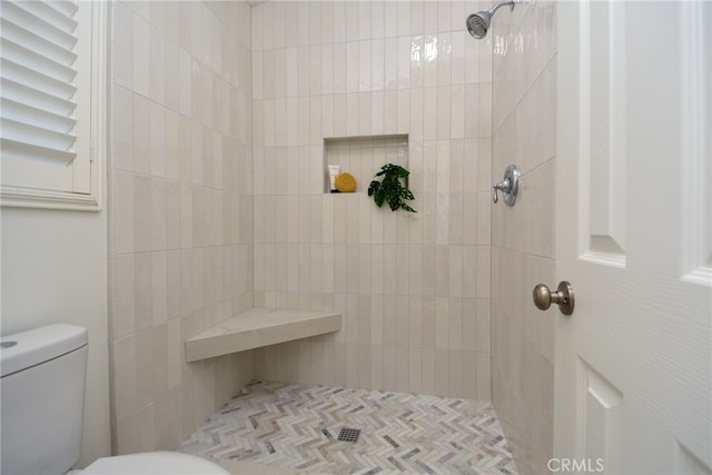 bathroom featuring toilet and tiled shower