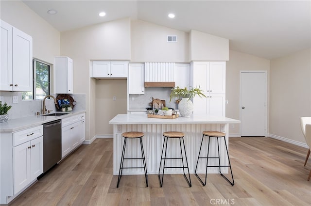 kitchen with lofted ceiling, dishwasher, a kitchen island, and sink