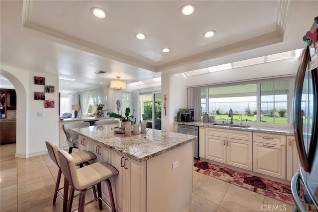 kitchen featuring a breakfast bar area, stainless steel appliances, sink, a center island, and light stone counters