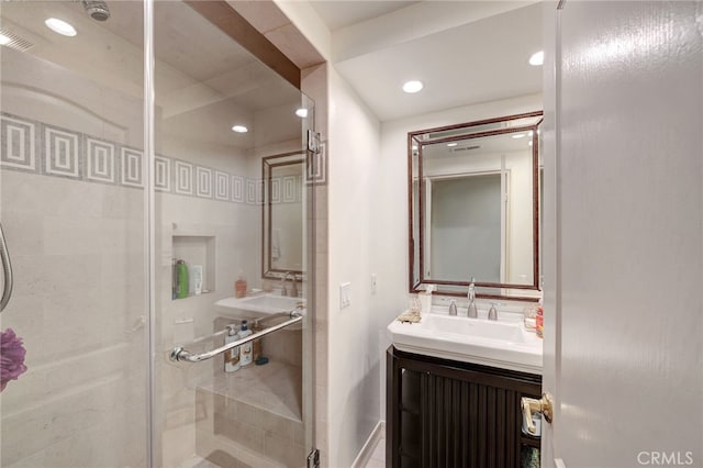 bathroom featuring a shower with door and vanity