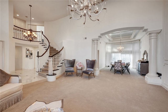 living room with a towering ceiling, a raised ceiling, decorative columns, ornamental molding, and light colored carpet