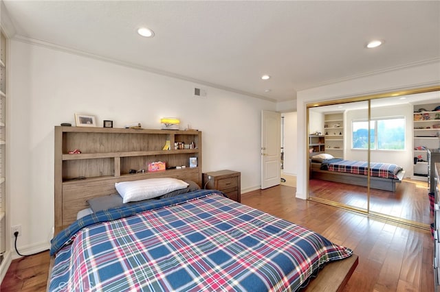 bedroom featuring a closet, ornamental molding, and dark hardwood / wood-style flooring