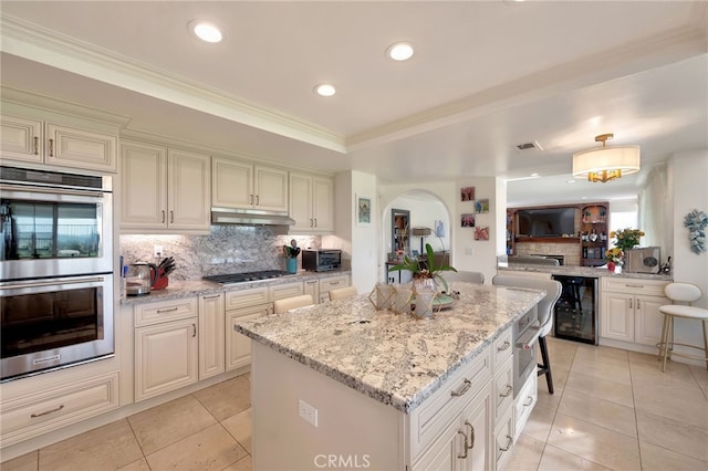 kitchen with light tile patterned flooring, backsplash, double oven, beverage cooler, and gas cooktop