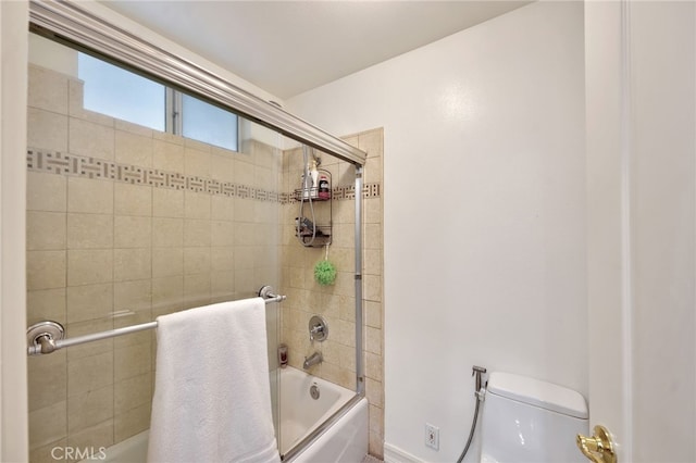 bathroom featuring combined bath / shower with glass door and toilet