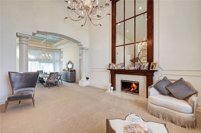 sitting room with ornamental molding, carpet flooring, a fireplace, and decorative columns