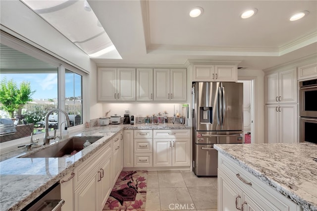 kitchen featuring crown molding, appliances with stainless steel finishes, sink, white cabinetry, and light stone counters