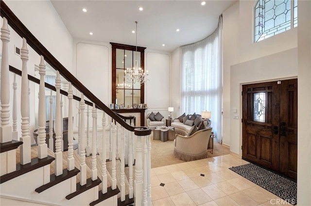 entryway featuring light tile patterned flooring, a wealth of natural light, a chandelier, and a high ceiling