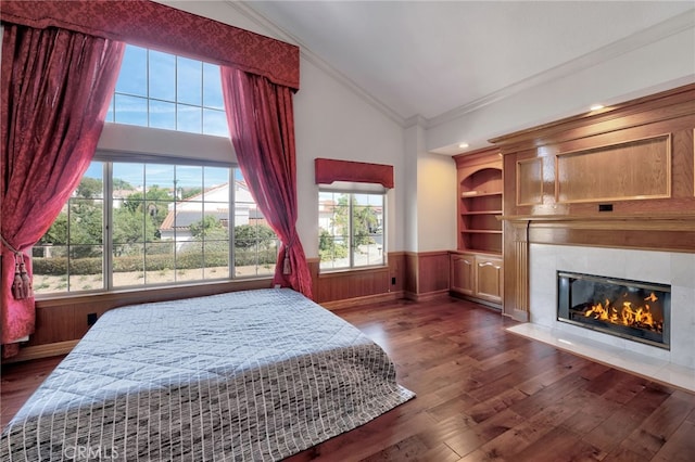 bedroom featuring multiple windows, dark hardwood / wood-style floors, a tile fireplace, and crown molding